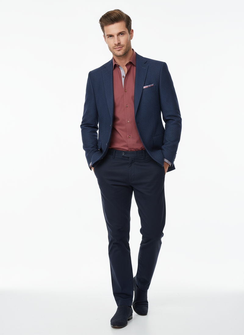Man wearing a navy blazer, red shirt, and dark pants on a white background